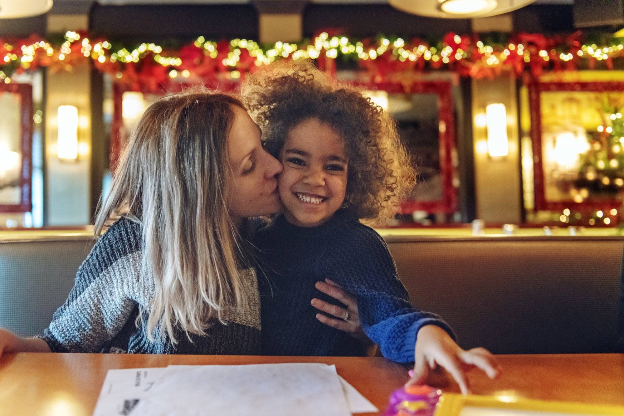 Multi-ethnic family shopping for Christmas, having a break in a restaurant