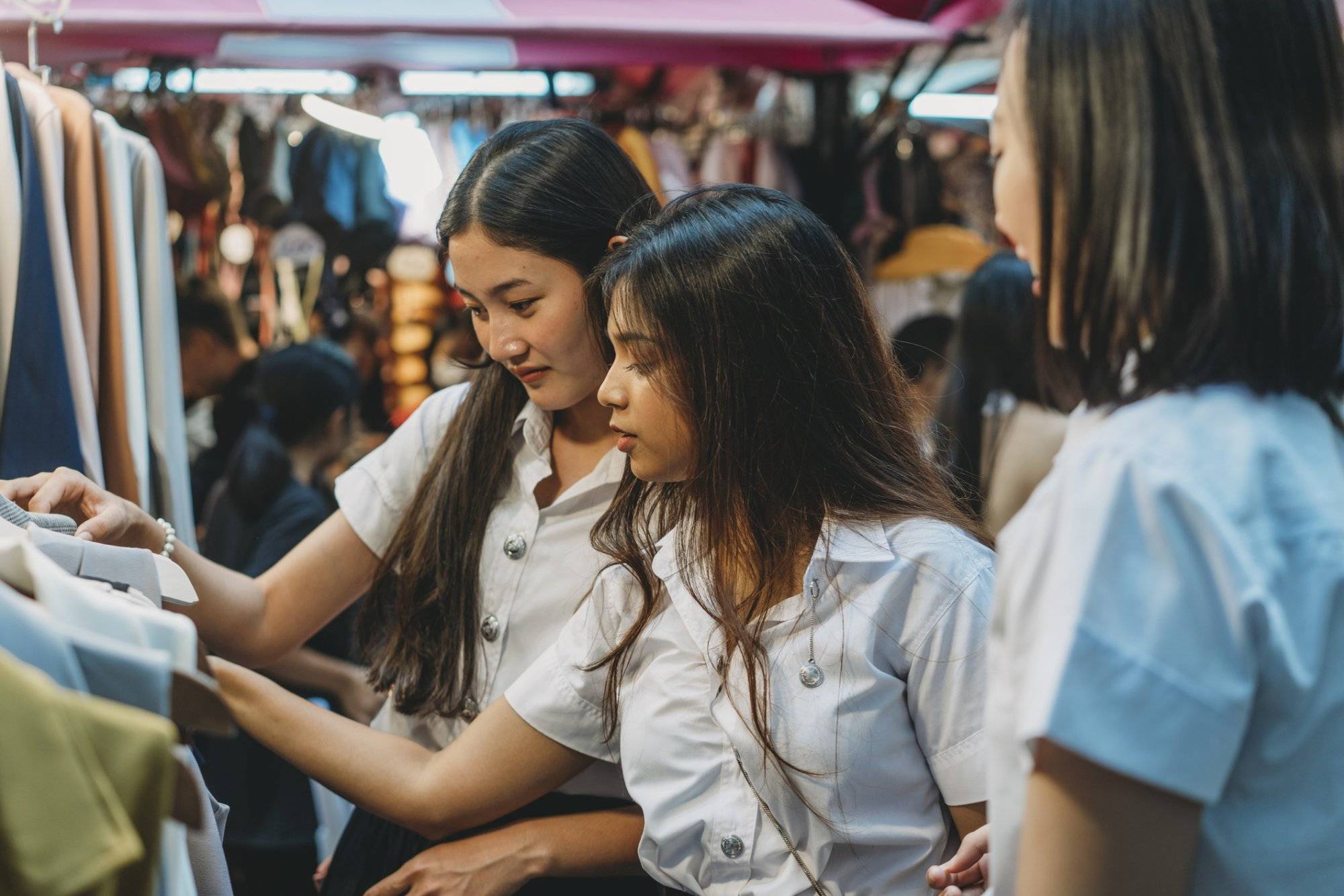 Three student friends doing shopping at the night market in the city